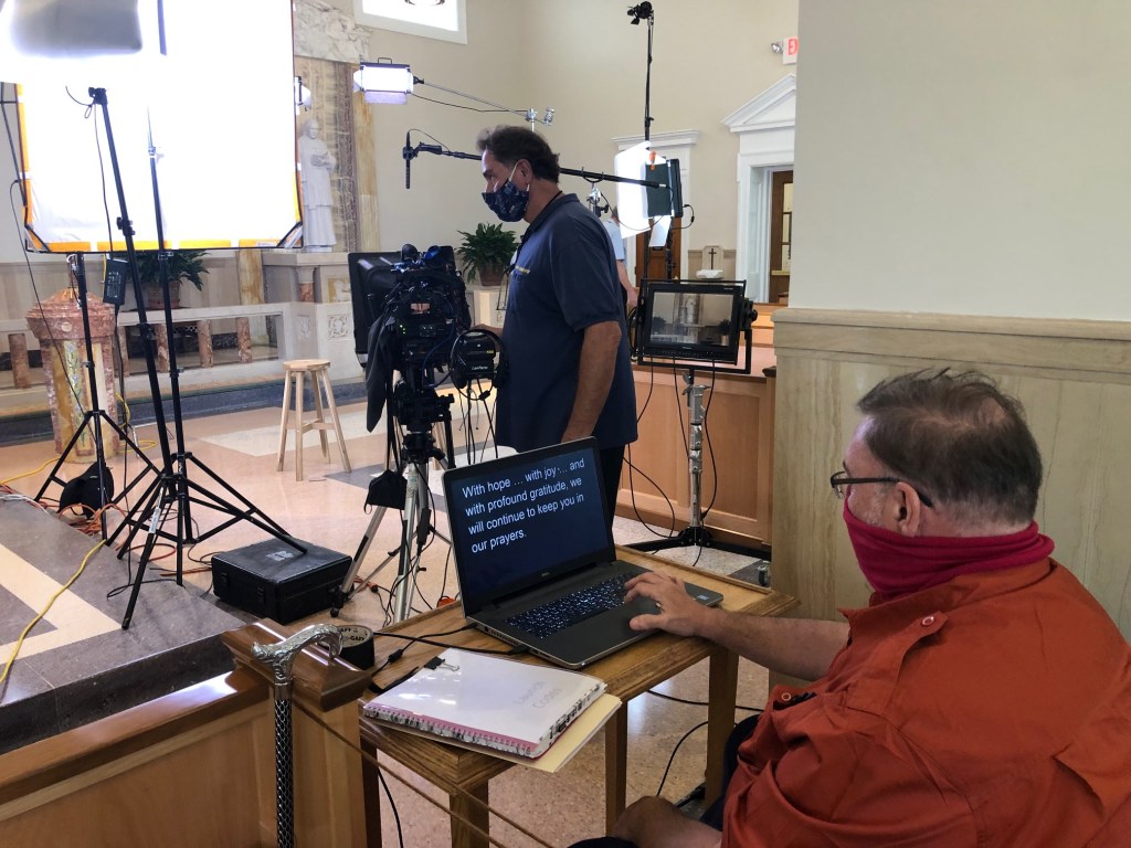 Camera operator and teleprompter technician shooting scene at remote location.